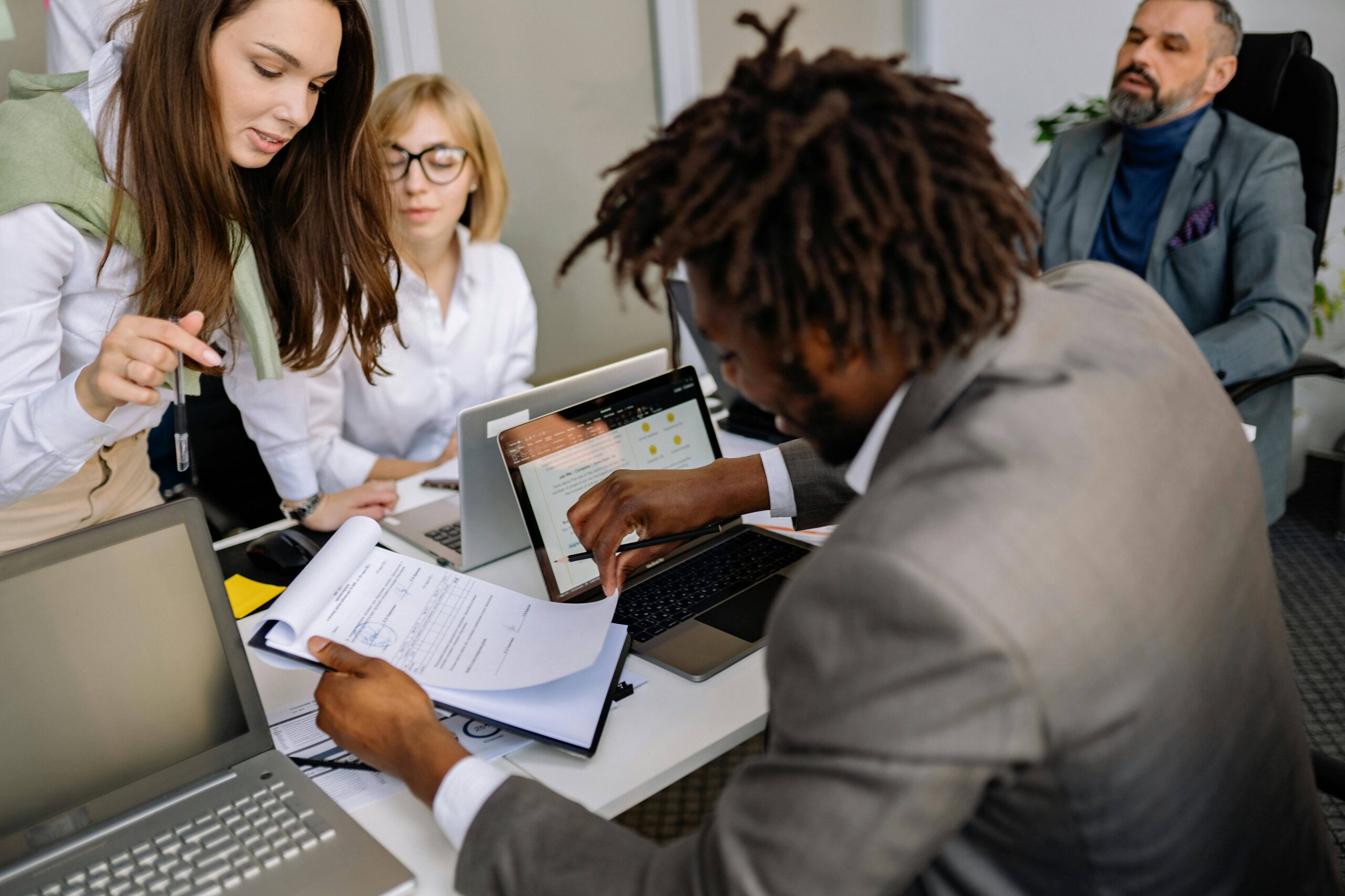 Équipe RH et managers collaborant autour de documents et d’un ordinateur, illustrant l’implication des parties prenantes dans un projet SIRH réussi – PeopleSpheres