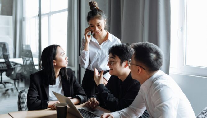 Équipe en réunion échangeant autour d’un ordinateur pour piloter un projet SIRH et accompagner la conduite du changement en entreprise. PeopleSpheres